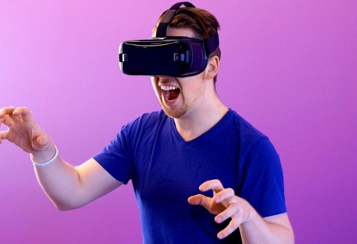 A male VR gamer with VR lens on, posing like a scary dragon